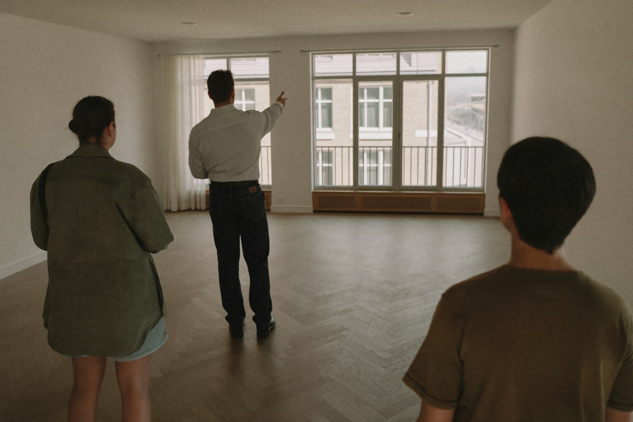 Drei Personen besichtigen eine leere Altbauwohnung